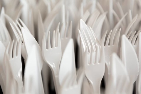 White plastic forks and knifes are seen stacked. Most disposable plastic utensils are made of