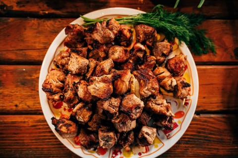 Shish kebab on skewers in a plate on a wooden table