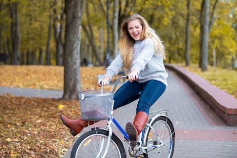 Young beautiful woman rides a bicycle in the autumn park