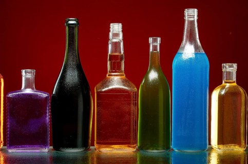 Verschiedene alkoholische Getränke in transparenten Flaschen auf rotem Hintergrund
