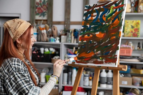 A talented woman artist passionately creates stunning abstract art within her vibrant and colorful