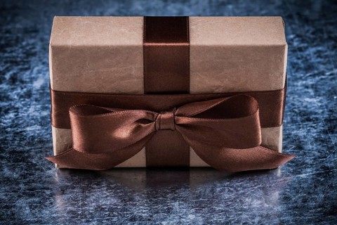 Present box with tied bow on metallic background holiday concept