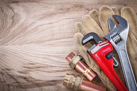 Safety gloves copper water pipe wrench hose nipples adjustable spanner on wooden board plumbing