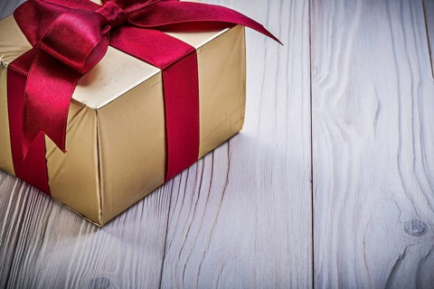 Present box with red knot on wooden board holidays concept