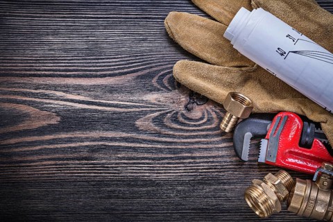 Working gloves pipe wrench engineering drawings brass plumbing fittings on wooden board copy space