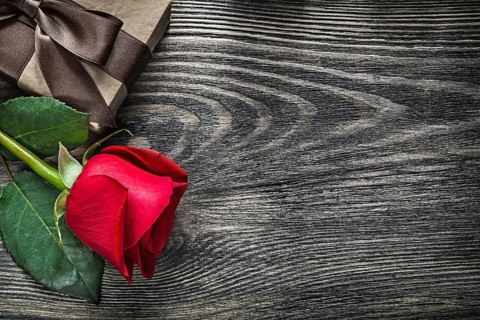 Red rose wrapped present box on wood board copy space holidays concept