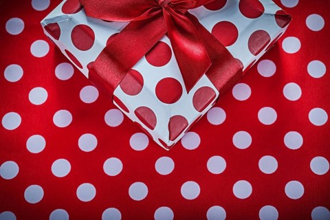 Present box with tied ribbon on polka-dot red tablecloth celebrations concept
