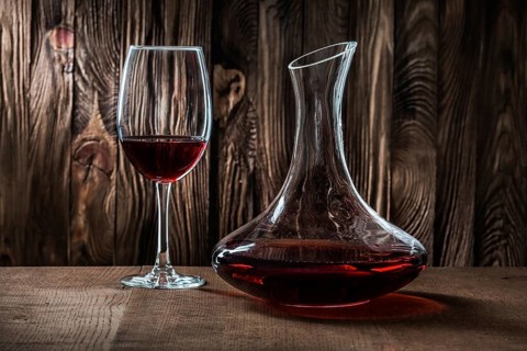 Decanter and glass with red wine on vintage wooden background