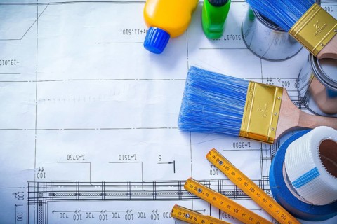 Duct tape safety gloves wooden meter and paint brush cans bottles on blueprint maintenance concept
