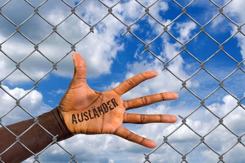 The hand of a foreigner behind a wire mesh fence, hole, loophole, help, refugee, asylum, migrant,