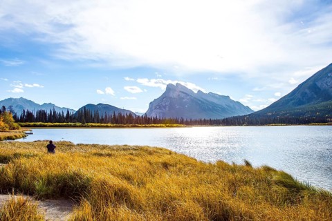 Woman photographing a magnificent lake in the Rocky Mountains of Canada. Travel to autumn. Lake