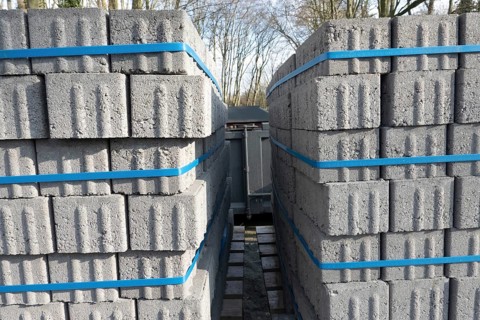 Concrete bricks, secured with blue straps, are being transported on a truck, ready for construction