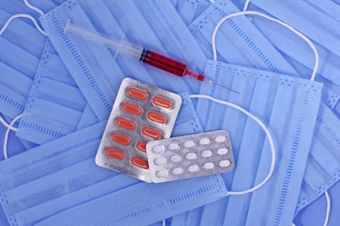 Protective medical mask, pills, syringe on blue background, corona virus protection, Concept of a