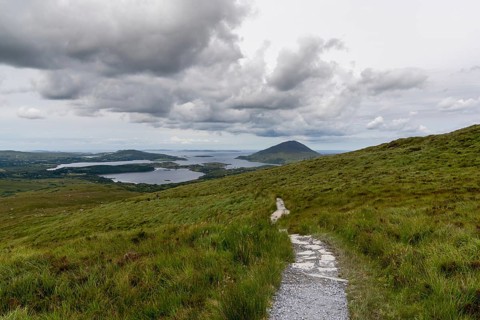 The hiking trail descending from Diamond Hill mountain peak in Connemara National Park with a view