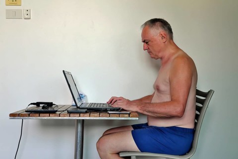 Businessman, freelancer, 60 plus on holiday working with laptop and mobile phone, Pattaya,