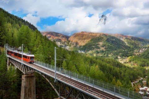 Zermatt, Switzerland. Gornergrat red tourist train on the bridge and Matterhorn peak panorama in