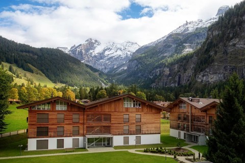 Wooden chalet in Kandersteg village, Canton Bern, Switzerland, Europe, Autumn trees and mountains