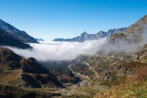 Situation on Susten pass on a sunny autumn day. View into the valley filled with fog with the pass