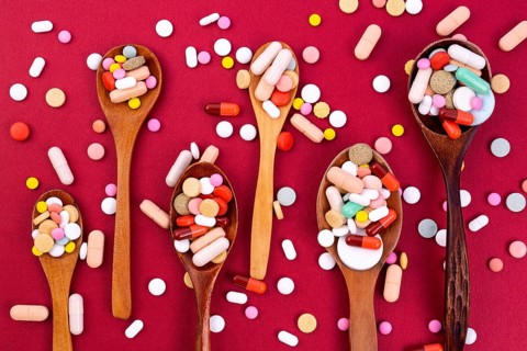 Different colorful pills and capsules in wooden spoons. Global pharmaceutical industry for billions