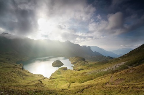 Autumn sunlight through clouds over alpine lake
