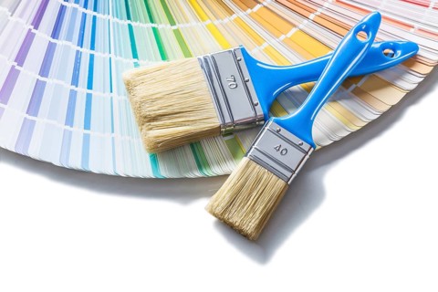 Two brushes with blue handles on color palette isolated on white