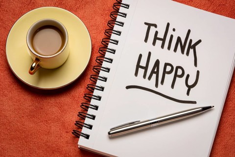 Think happy inspirational handwriting in a sketchbook with a cup of coffee, personal development,