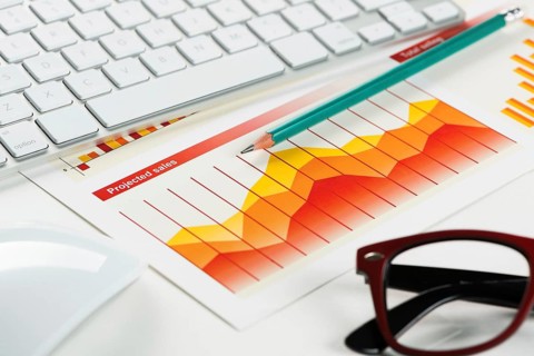 Business workplace with keyboard glasses and financial documents on table