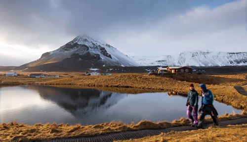 Arnarstap, Iceland, March 21 2016: People walking around a lake with snowy mountain reflected on