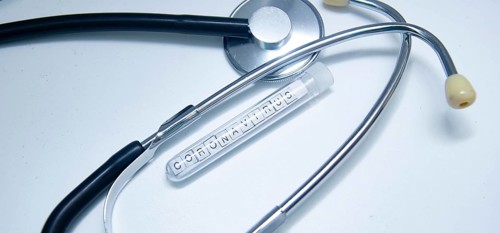 Coronavirus-labeled test tube beside a stethoscope on a white background
