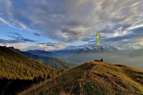 Sitting woman enjoying a dreamlike evening mood in the mountains, view to the Rätikon, flag of the