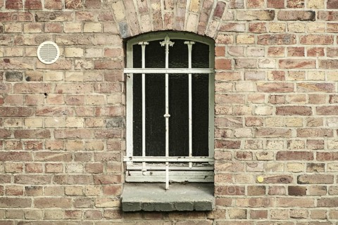 Barred cellar window in a brick wall
