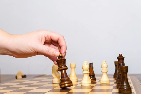Close-up of a woman's hands playing chess with a white background and copy space