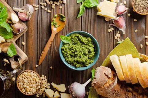 Flat lay view at food background with genovese pesto sauce and its ingredients on wooden kitchen