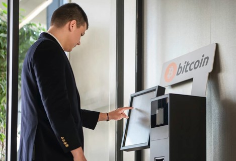 Young businessman buying cryptocurrency on ATM