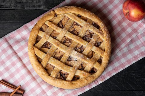 Above view of a delicious homemade apple pie with a lattice crust, on a pink towel, on a wooden