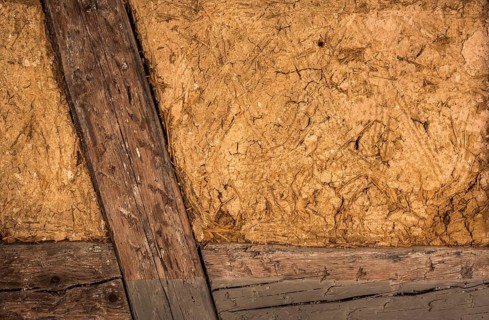 Clay house wall, with details on the wooden beams and the mixture of mud and straw, perfect as