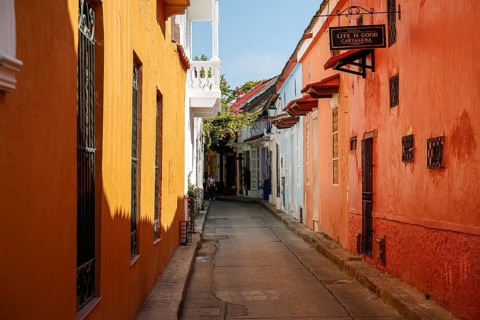 Narrow street in the old town of Cartagena with colorful one-story houses in sunlight and shadow,