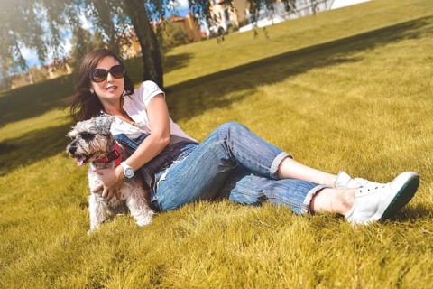 Pretty adult caucasian happy woman resting in the park on a sunny day with her beloved dog. Female