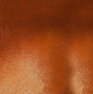 Metallic textured background in shades of orange reflecting light and creating a gradient effect