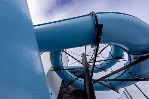 An exciting and vibrant blue water slide elegantly twisting through the bright sky at a popular