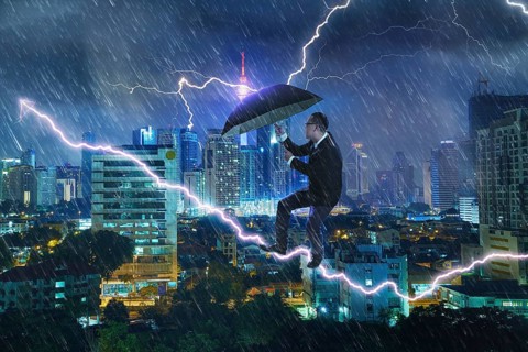 Junger Geschäftsmann mit Regenschirm gegen Gewitter. Herausforderungen und Krisenkonzept zu