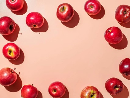 Red apples on orange or coral pink background with copy space for text or design in center.
