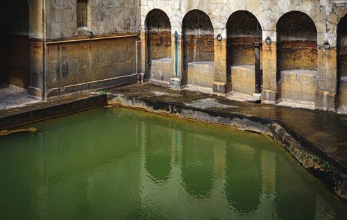 Water and buildings in an old roman bath in the city of Bath in the united kingdom england