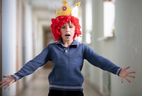 Child with a red wig and a crown. Clown boy