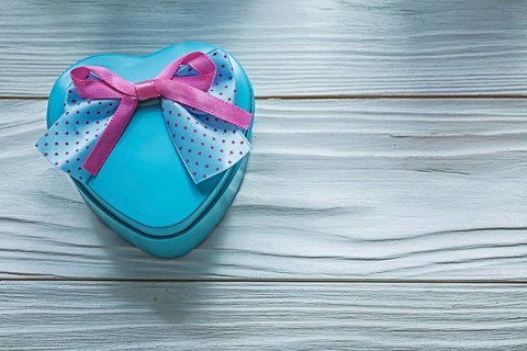Heart-shaped blue gift box with pink bow on wooden board holidays concept