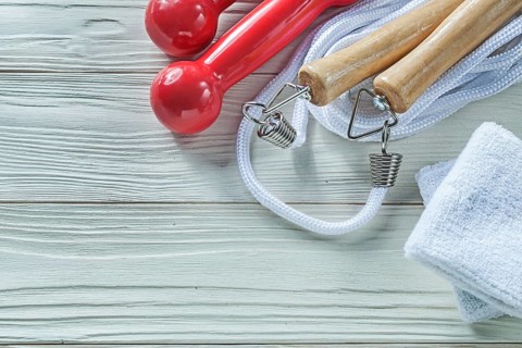 Skipping rope sweatbands dumbbells on wooden board fitness concept