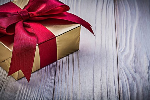 Present box with red ribbon on wooden board holidays concept