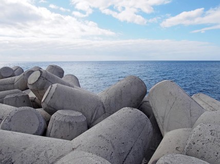 Concrete interlocking tetrapods used to prevent coastal erosion placed on a shoreline with a blue