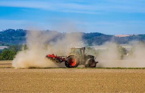 A farmer cultivates his parched field with a tractor during a dry period. Austria, Upper Austria,