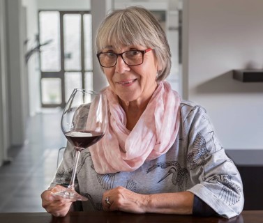 Senior citizen drinks wine at a table